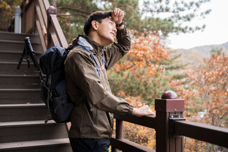 Asian handsome man trekking, climbing autumn mountainの写真素材