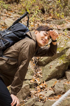 Asian handsome man trekking, climbing autumn mountain