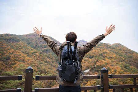 Asian handsome man trekking, climbing autumn mountainの写真素材