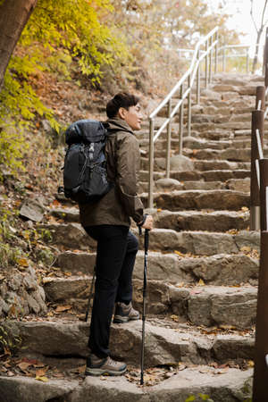 Asian handsome man trekking, climbing autumn mountain