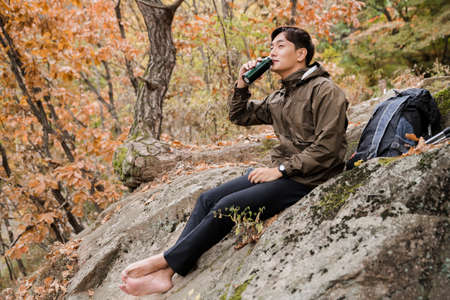 Asian handsome man trekking, climbing autumn mountainの写真素材