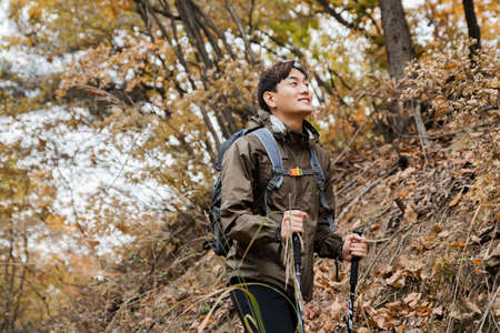 Asian handsome man trekking, climbing autumn mountain