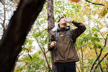 Asian handsome man with mask trekking, climbing autumn mountain