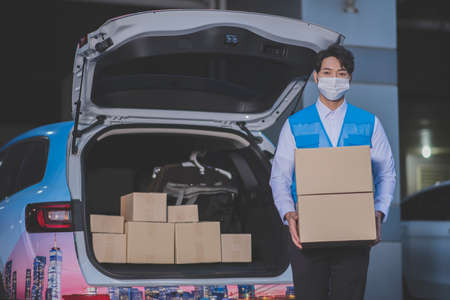 Asian delivery man wearing mask holding boxes