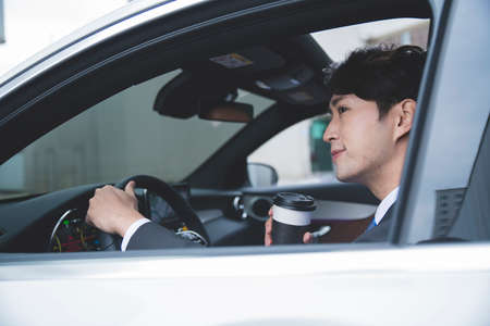 Asian male in suit with coffee in the car, business concept