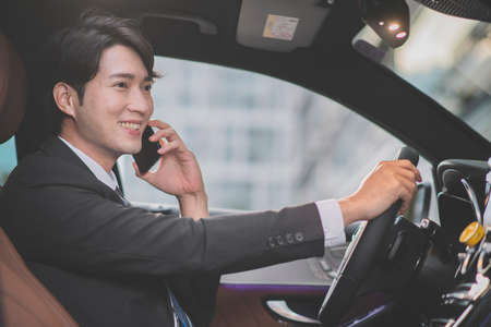 angry Asian male in suit using mobile phone in the carの写真素材