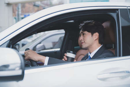 Asian male in suit with coffee in the car, business conceptの写真素材