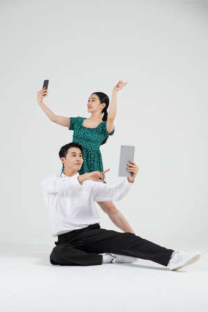 Asian couple contemporary dancers holding tablet and smartphoneの写真素材