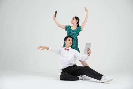 Asian couple contemporary dancers holding tablet and smartphoneの写真素材