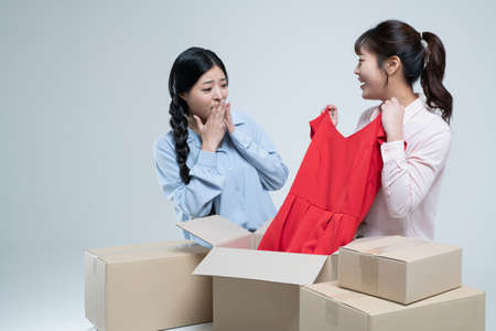 two Asian women, sisters unboxing delivery box on floorの写真素材