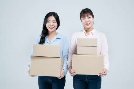 two Asian women, sisters carrying boxesの写真素材