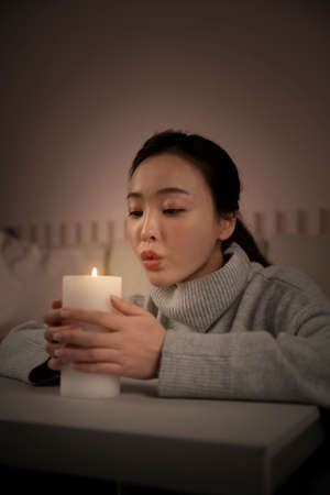 Asian woman and scented candle at home