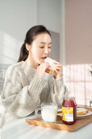 Asian woman having brunch, toast with jam at home
