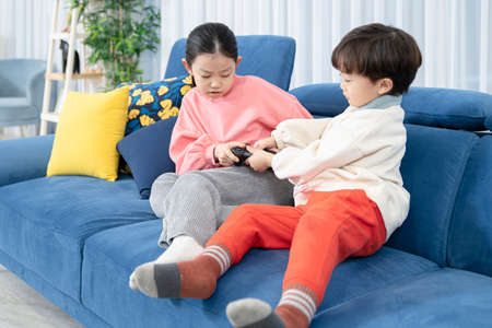 Asian boy and girl fighting, family concept spending time at homeの写真素材