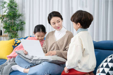 Asian mom and children, sister and brother family concept spending time at homeの写真素材