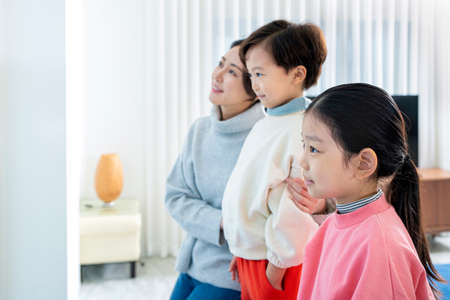 Asian mom and children smiling at windowの写真素材