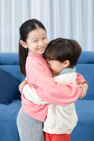Asian children, sister and brother hugging after fightの写真素材