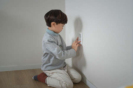 Asian boy inserting finger into an electrical outlet