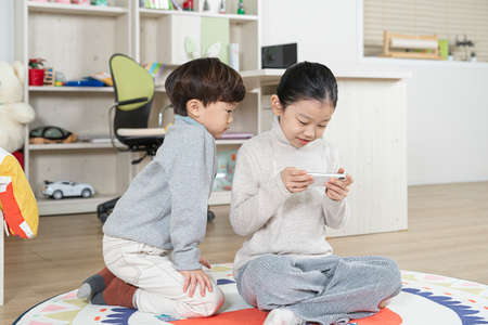 Asian girl and boy, sister and brother playing with smartphoneの写真素材