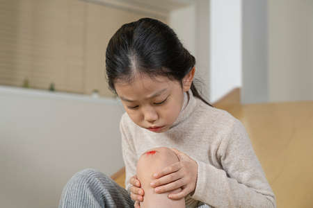 Asian little girl with wound on knee due to slideの写真素材