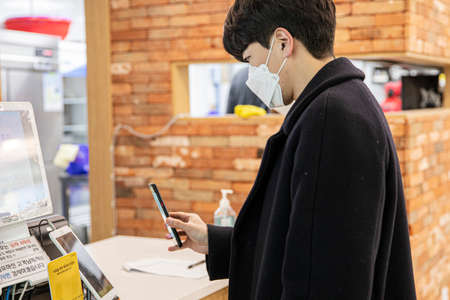 Asian man with mask scanning QR code