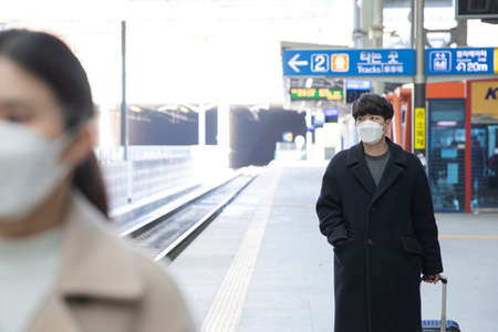 Asian man and woman wearing masks in public transportation