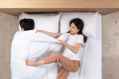 Asian couple fighting over blanket