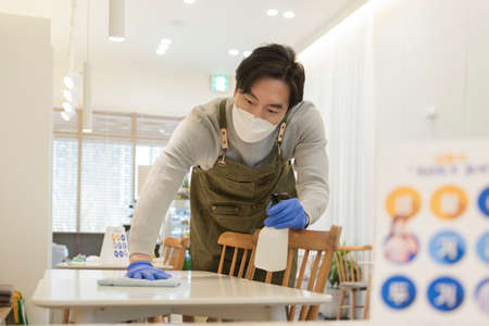 Asian man with mask sanitizing store