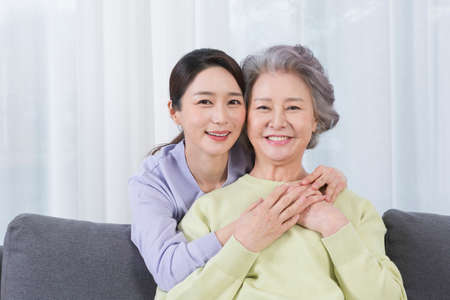 happy smiling Asian old mother and middle aged daughter on sofaの写真素材