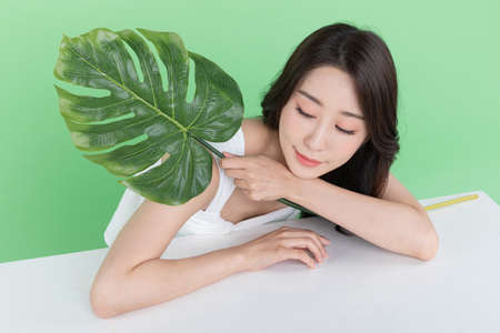 summer beauty concept, beautiful Korean Asian woman holding green leavesの写真素材