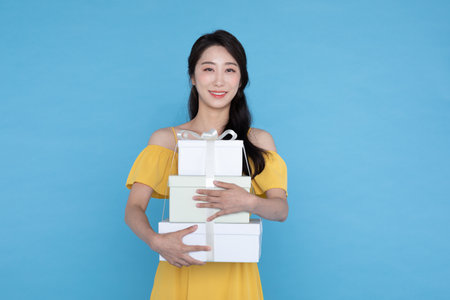 shopping event concept, beautiful Korean Asian woman in yellow summer holding gift boxdelivery boxの写真素材