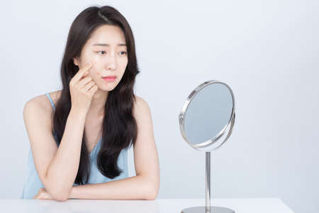 Asian woman with acne, pimple skin trouble on cheekの写真素材