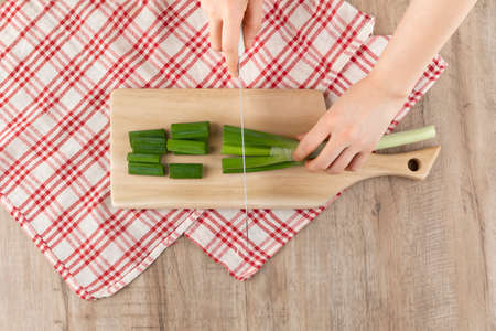cutting green onion with a knife on the cutting board