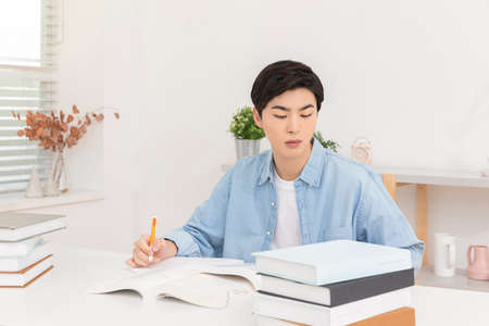 young Asian male studying with booksの写真素材