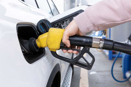 hand holding fuel nozzle at gas station