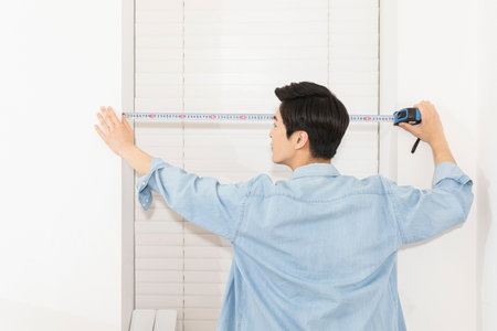 young Asian man measuring window lengthの写真素材