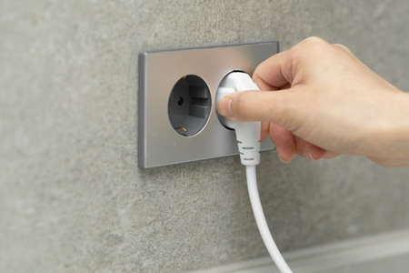 hand plugging out cord from outlet