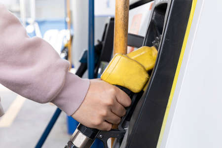 hand holding fuel nozzle at gas station