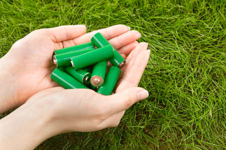 green eco battery on two hands, grass backgroundの写真素材