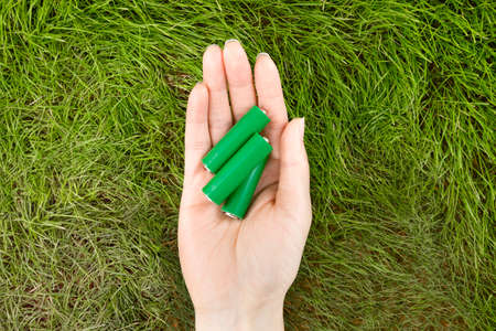 green eco battery on two hands, grass backgroundの写真素材