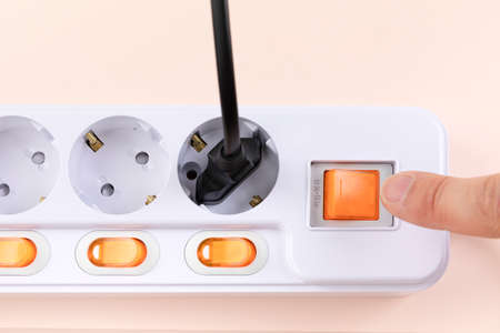 hand turning on switch of power strip