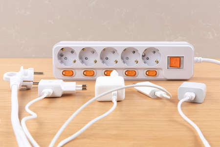 many chargers plugged to power strip plug, wood background