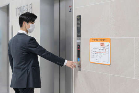 Asian man employee with mask riding elevator