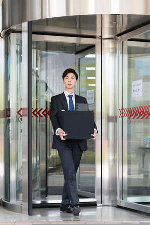 young Asian handsome employee man quitting job, holding boxの写真素材