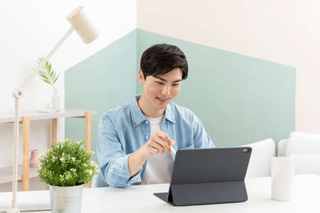 Asian young man using tablet device and digital pen