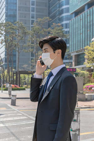 Asian man employee with mask talking on smartphone