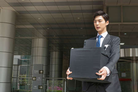 young Asian handsome employee man quitting job, holding boxの写真素材
