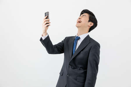 Asian man businessman laughing at smartphoneの写真素材