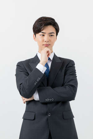 worried Asian man worker, businessman with hand on chinの写真素材