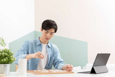 Asian young man learning chess through online class using tablet deviceの写真素材